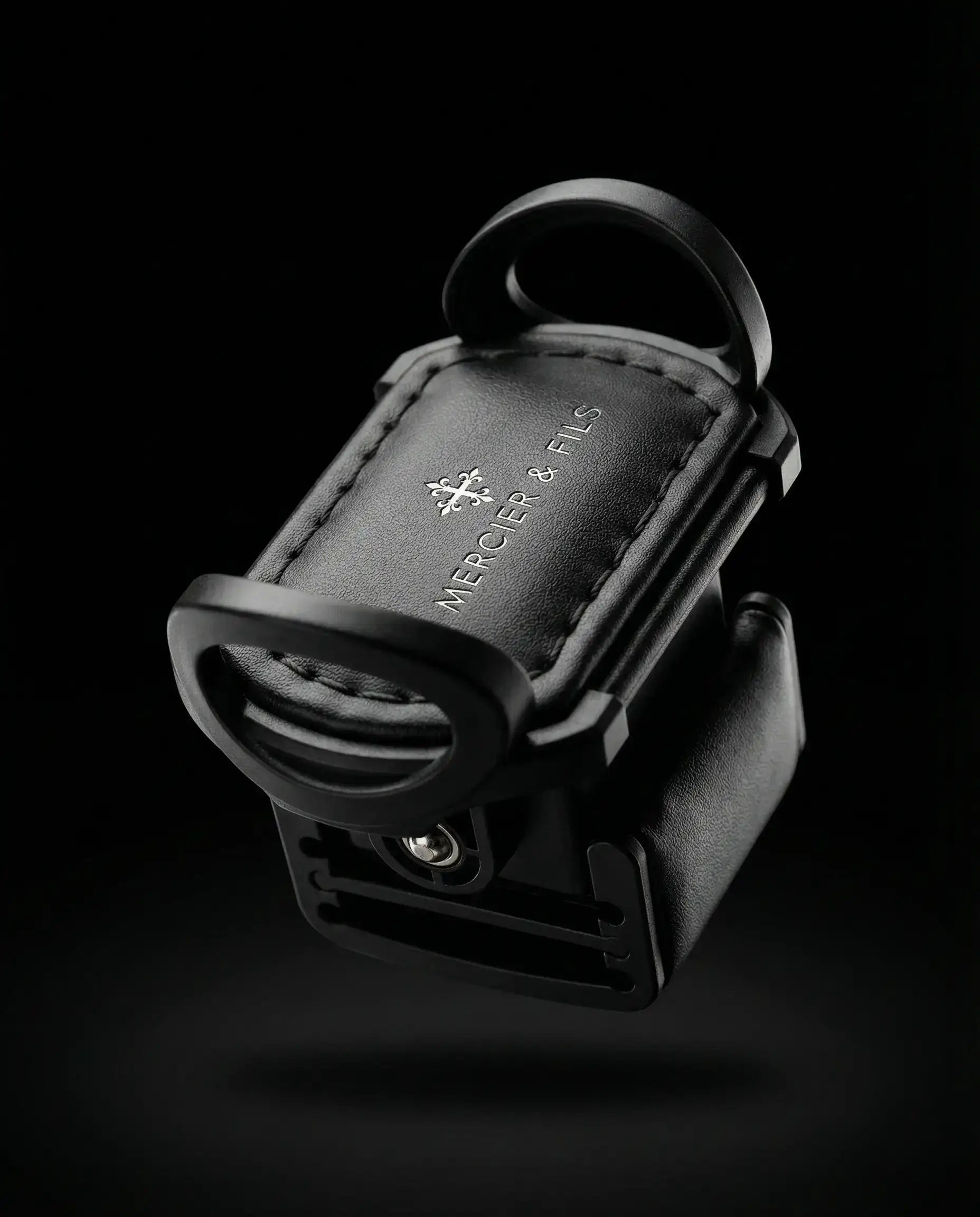 Support de téléphone en cuir noir avec un marquage « mercer & fils » en relief et un design élégant et minimaliste.