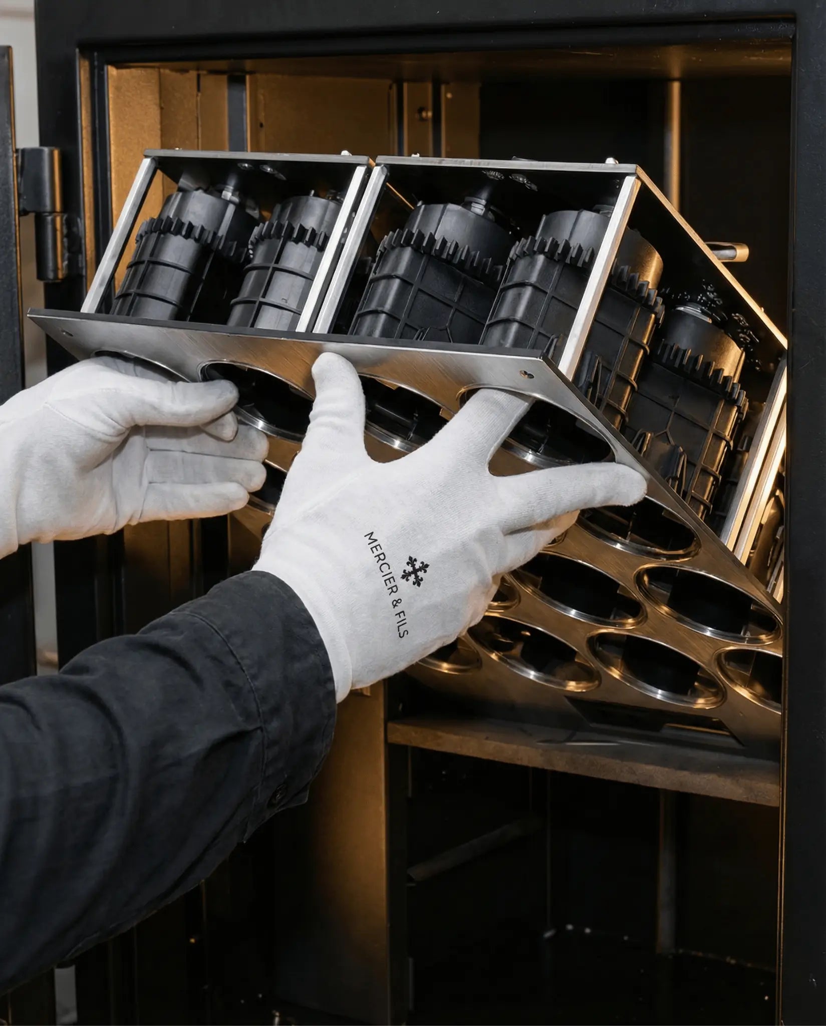 Technicien Mercier & Fils en gants blancs logoés assemblant les modules de remontage d'un remontoir montre automatique, mécanique intérieure visible